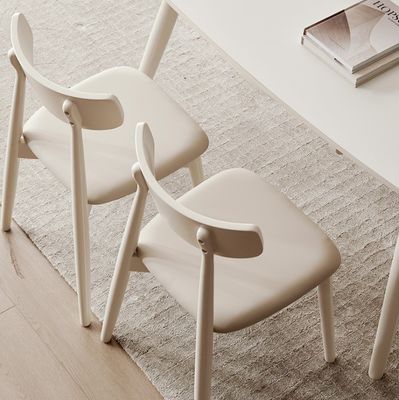 Silla de comedor de estilo nórdico con patas de madera maciza y cubierta de tela en acabado de nitrolaca