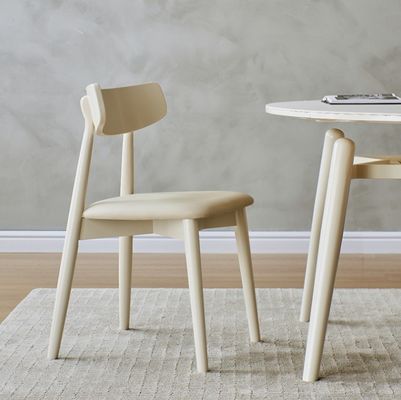 Silla de comedor de estilo nórdico con patas de madera maciza y cubierta de tela en acabado de nitrolaca